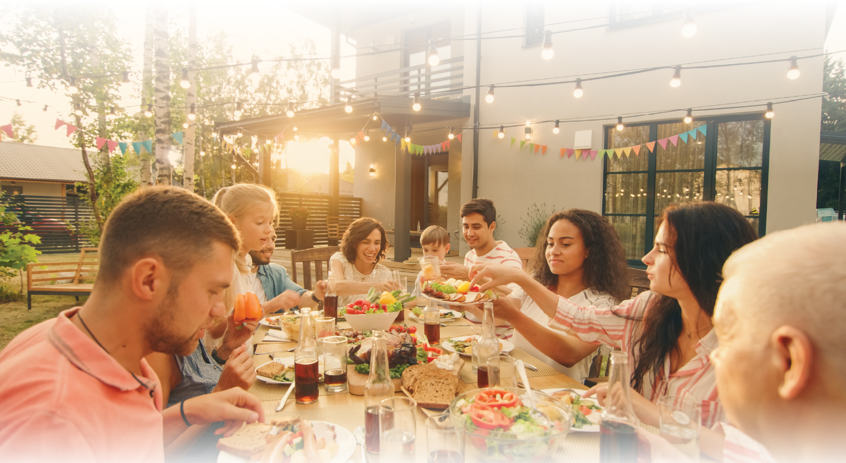 Image of large group of family and friends dining outdoors and serving food in new outside entertaining space. 